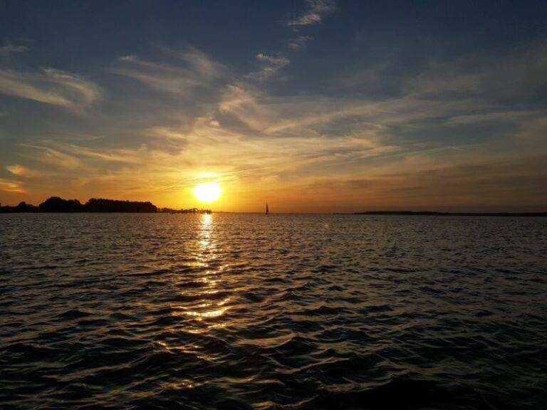 Während der Klassenfahrt versinkt die Sonne hinter einem Segelboot in der Ostsee